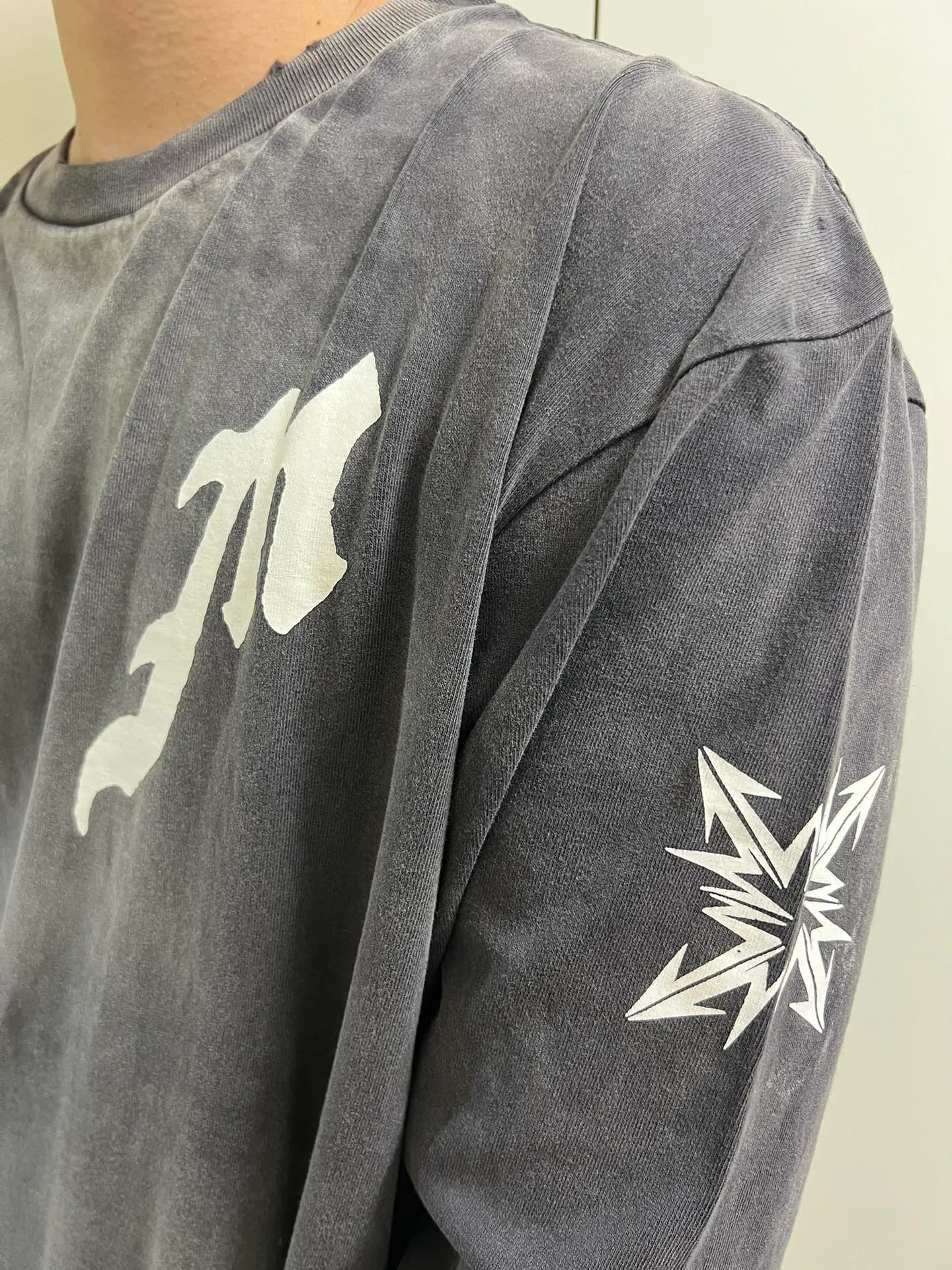 SAINT Mxxxxxx M/AFTER LS_TEE/BLACK Flame arrow Letter M retro distressed long tee Washed black S-XL Tubular fabric Assute ready-made garments dyed The whole piece is sprayed with horse-hair spray and then sprayed again to fade the color. The collar and cuffs are frayed. Many places are frayed. Extra large printing position. Very difficult to print. Complete accessories. With little angel anti-counterfeiting label.